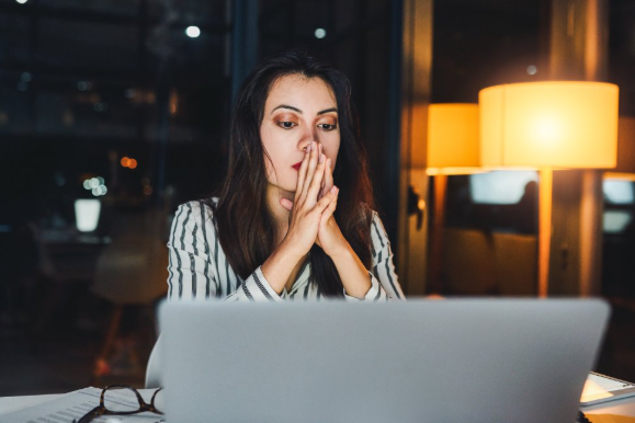 Photo of a woman looking at a laptop screen with her head in her hands